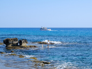 Fototapeta premium fisherman catches fish on the rocky seashore