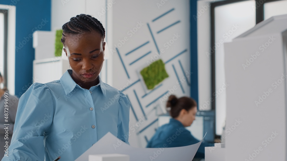 Poster portrait of woman architect analyzing blueprints plans to design construction layout and structure. 