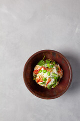 Chef salad with crab, quinoa, vegetables and edamame beans on dark homemade ceramic bowl. Salad bowl with crab, avocado, cream sauce in modern serveware. Modern dishware on concrete background.