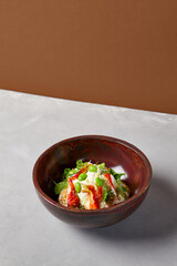 Chef salad with crab, quinoa, vegetables and edamame beans on dark homemade ceramic bowl. Salad bowl with crab, avocado, cream sauce in modern serveware. Modern dishware on concrete background.