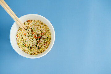 instant noodles with wooden chopsticks on a blue background, top view. Korean national dish.
