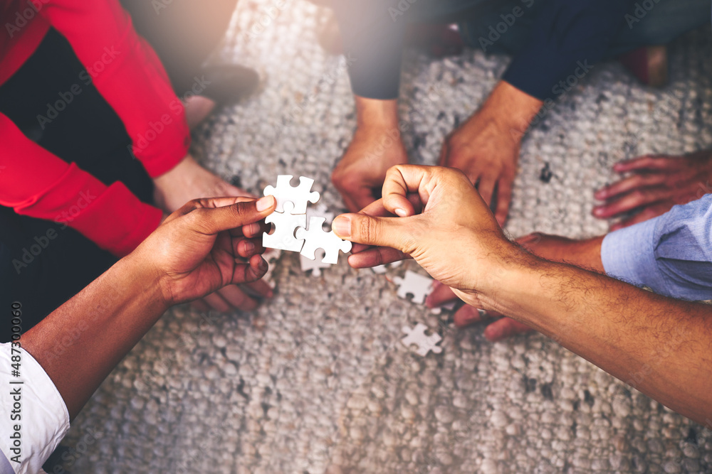 Poster finding solutions piece by piece. shot of a group of unidentifiable businesspeople building a puzzle