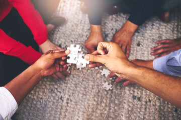Finding solutions piece by piece. Shot of a group of unidentifiable businesspeople building a puzzle together.