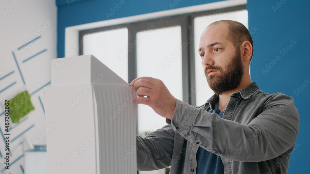 Poster close up of man engineer designing building model and maquette layout for architecture work. archite