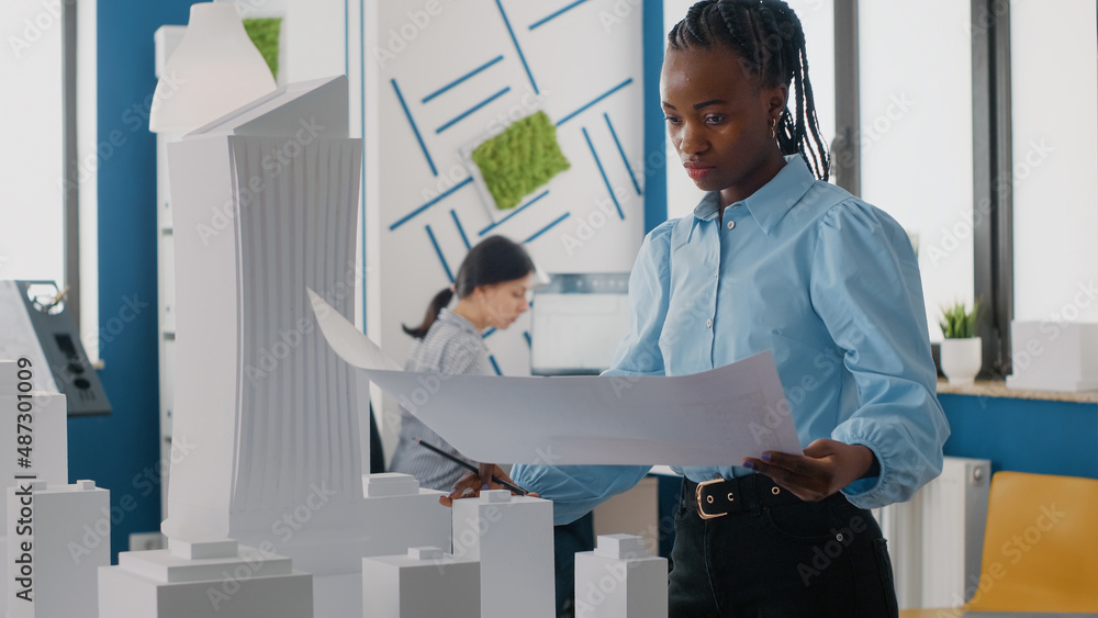 Poster close up of woman engineer analyzing blueprints plan and building model for development. expert arch