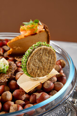 Appetizers set on luxury plate with hazelnut. Creative platter of appetizers from inspirational chef. Salmon cheesecake, fish tartar, pastrami crocket, liver pate, baked mini-paprika