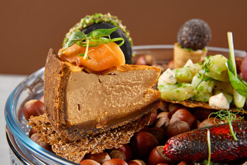 Appetizers set on luxury plate with hazelnut. Creative platter of appetizers from inspirational chef. Salmon cheesecake, fish tartar, pastrami crocket, liver pate, baked mini-paprika