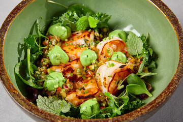 Green bowl with prawns, quinoa and avocado cream on handmade ceramic plate. Salad with shrimp in dark modern dishware. Healthy food in contemporary style