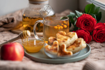 composition with a glass teapot and a glass mug with sea buckthorn tea and cakes