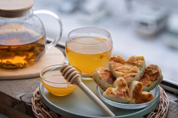 composition with a glass teapot and glass cup filled with tea and cake on the plate