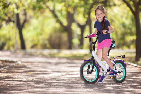 Happy cute girl with bicycle in the spring park. Beauty nature scene with healthy outdoor lifestyle. Happy kid having fun outdoor at summer. Happiness and harmony