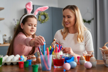 Happy caucasian family of two people decorates easter eggs at home