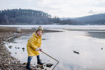 Happy little boy with Down syndrome looking at camera outside by lake in winter.