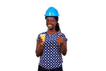 beautiful young female engineer holding a cup of coffee and showing her thumb.