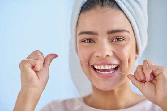 Taking care of my smile. Cropped portrait of a beautiful young woman flossing her teeth in the bathroom at home.