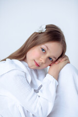 A beautiful cheerful little girl about 10 years old in a beautiful dress on an isolated white...
