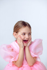 A beautiful cheerful little girl about 7 years old in a beautiful dress on an isolated white background.A place for your text.