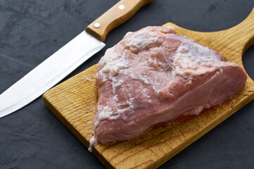a piece of meat on a chopping board and a knife next to it