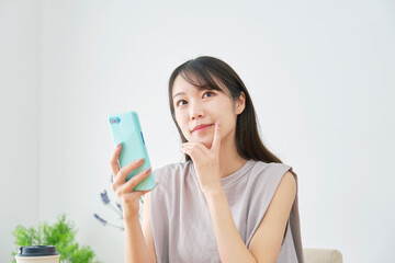 女性　スマホ　想像する　リビング