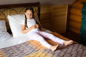 Young girl lying on large double bed covered with gray yellow blanket with body on white pillow...