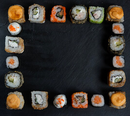 A variety of sushi with wooden desk on black slate background. Asian food frame. Dinner party.Top view.