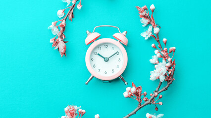 Spring blossom. May flowers and April floral nature with alarm clock on blue background. Branches of blossoming apricot macro with soft focus. For easter greeting cards with copy space. Springtime.