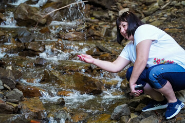 woman enjoying the coolness of a waterfall, female hiker, woman in front of flowing water