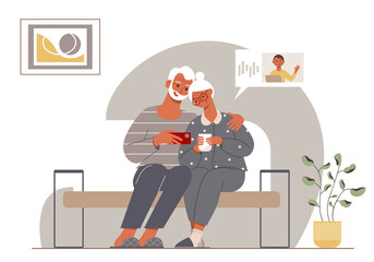 Modern elderly couple talking with their grandson online. Stylish grandpa and grandma sitting on a sofa in a cozy home.