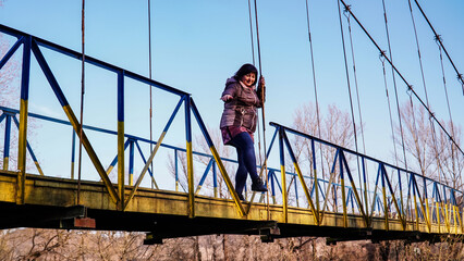 woman jumping from a bridge, old iron bridge, early spring 