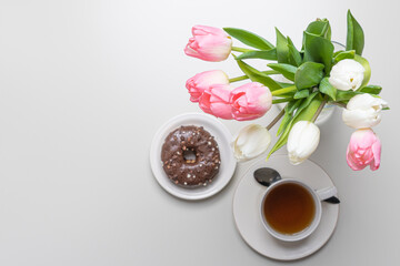 Obraz na płótnie Canvas donuts, a cup of coffee, and tulips on top. Concept, breakfast and spring, holidays, spring holiday.
