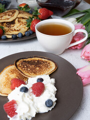 Sweet homemade pancakes with blueberries and strawberries jam and sour cream. tea on a white background, view from the top. The concept of breakfast, snacks and nutrition. Maslenitsa.