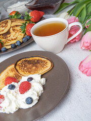 Sweet homemade pancakes with blueberries and strawberries jam and sour cream. tea on a white background, view from the top. The concept of breakfast, snacks and nutrition. Maslenitsa.