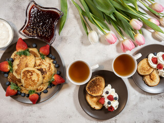 Sweet homemade pancakes with blueberries and strawberries jam and sour cream. tea on a white background, view from the top. The concept of breakfast, snacks and nutrition. Maslenitsa.