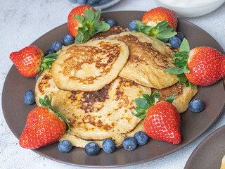 Sweet homemade pancakes with blueberries and strawberries jam and sour cream. tea on a white background, close-up. The concept of breakfast, snacks and nutrition. Maslenitsa..