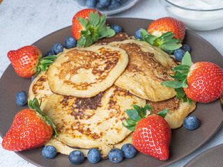 Sweet homemade pancakes with blueberries and strawberries jam and sour cream. tea on a white background, close-up. The concept of breakfast, snacks and nutrition. Maslenitsa..