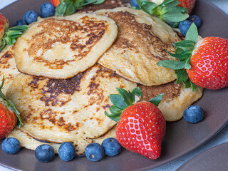 Sweet homemade pancakes with blueberries and strawberries jam and sour cream. tea on a white background, close-up. The concept of breakfast, snacks and nutrition. Maslenitsa..
