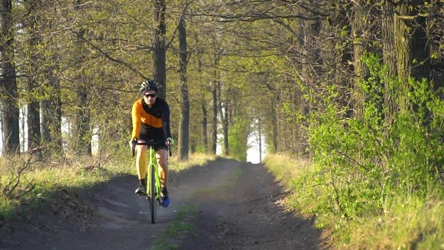 Silhouette of a cyclist on a gravel bike riding a trail in the forest