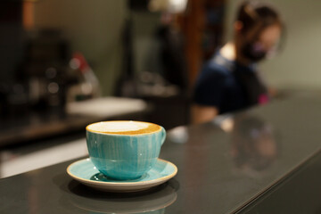 A cup of beautiful ceramic with coffee or cappuccino stands on the bar counter on the table