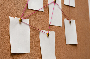 Blank paper notes are pinned to a cork board. The concept of detective investigation. Copy space.