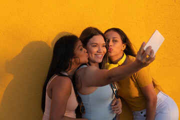 Three Latina women in the park posing and taking selfies