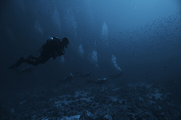 divers underwater at depth in the blue sea background
