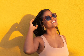 African woman standing with casual clothes and space to copy. Beautiful positive woman in front of yellow background.