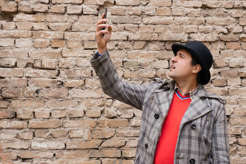 A man with a phone in his hand on the background of a brick wall