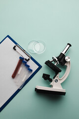 Microscope, test tubes and watch glass on a blue background. Laboratory or analysis theme. Vertical...