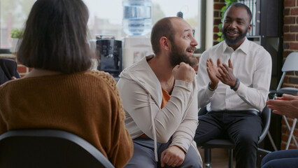 Man doing handshake with people after sharing progress and success at aa group meeting. Adult celebrating achievement with patients clapping hands at rehabilitation therapy program.