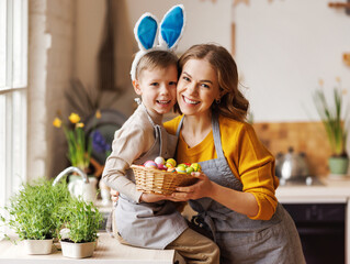 Sweet family portrait of young mother and little son with wicker basket full of painted Easter eggs