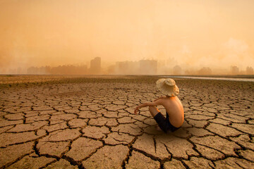 Young man sitting on drying river and looking to polluted city with smoke of co2, carbon dioxide on...