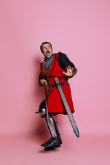 Full-length portrait of scary man, medieval warrior or knight in armor clothing, red costume...