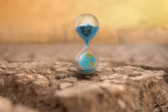 Hourglass On Dry Cracked Earth With Melting Iceberg And Globe, Factory And Industry Release Co2, Carbon Dioxide Gas On Background Metaphor Climate Change Impact To Environment, Global Warming Effect.