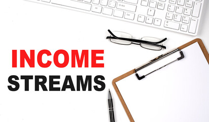 INCOME STREAMS text written on white background with keyboard, paper sheet and pen